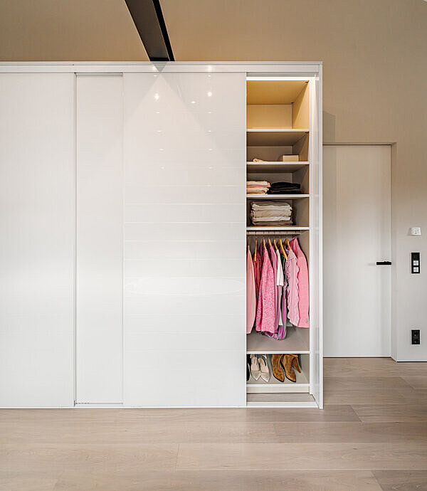 Moderner Glas Kleiderschrank mit weißen Schiebetüren im Schlafzimmer verbaut.