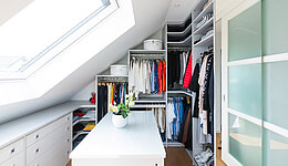 Weißer Einbauschrank als Ankleidezimmer unter einer Dachschräge verbaut