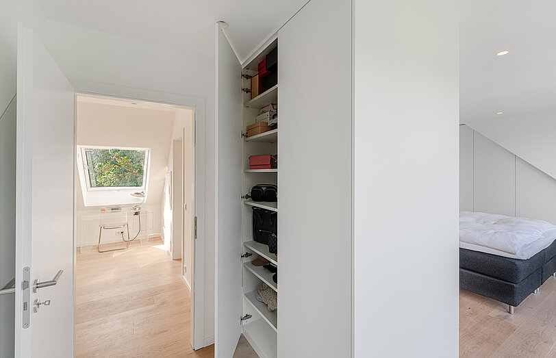 Weißer Einbauschrank nach Maß im Schlafzimmer, der gleichzeitig auch als Raumteiler genutzt wird.