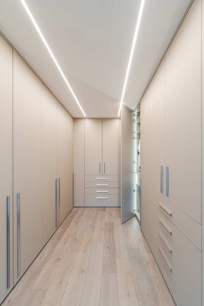 Das luxuriöse Ankleidezimmer mit maßgeschneiderten Schränken und eleganten Türen nutzt den gesamten Raum und vereint Stil mit Funktionalität.