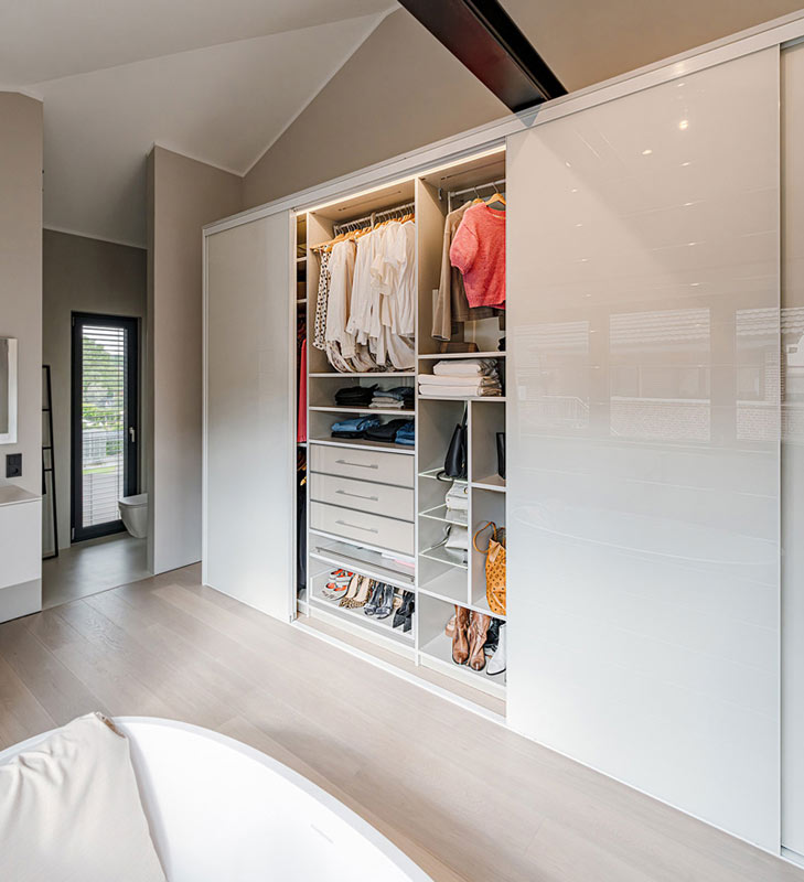 Dieser maßgefertigte Schrank fügt sich nahtlos in das moderne Schlafzimmer ein und kombiniert Funktionalität mit Ästhetik. Die hochglänzende Schiebetür gleitet elegant zur Seite und enthüllt ein perfekt organisiertes Inneres.