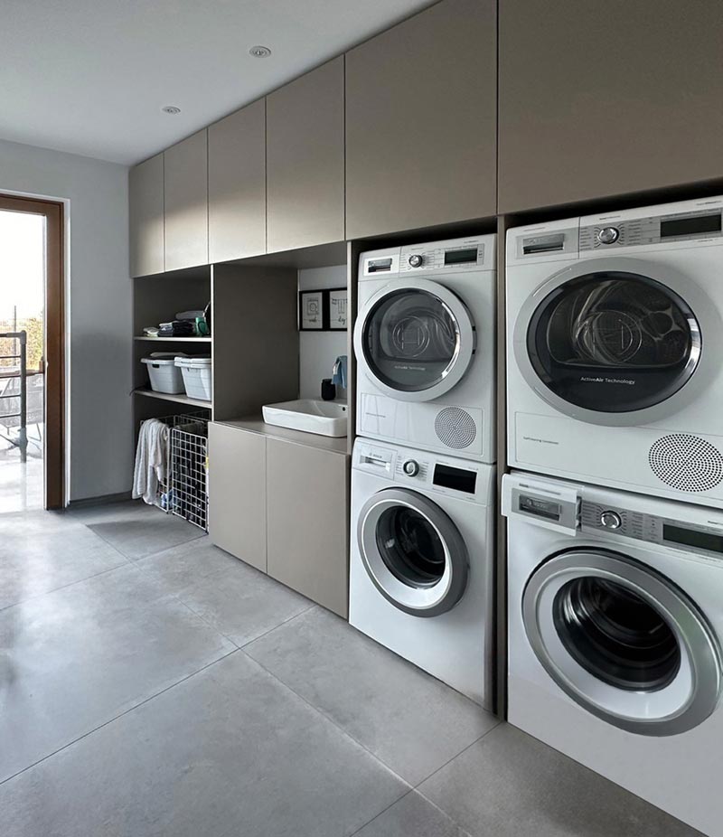 Moderner Mehrzweckschrank für Waschmaschine und Trockner in Taupe im Hauswirtschaftsraum eingebaut