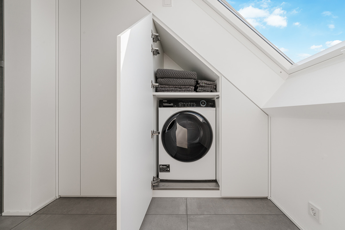 Maßgefertigter Schrank unter einer Schräge verbaut, der Platz für die Waschmaschine bietet
